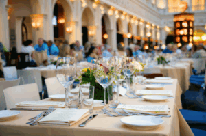 Elegant outdoor dining setup at a luxury Singapore venue, featuring beige tablecloths, floral centerpieces, and meticulously arranged tasting menus. Guests seated in the background enjoy a curated multi-course experience under warm architectural lighting, evoking the sophistication and sensory richness of Singapore’s best tasting menus.