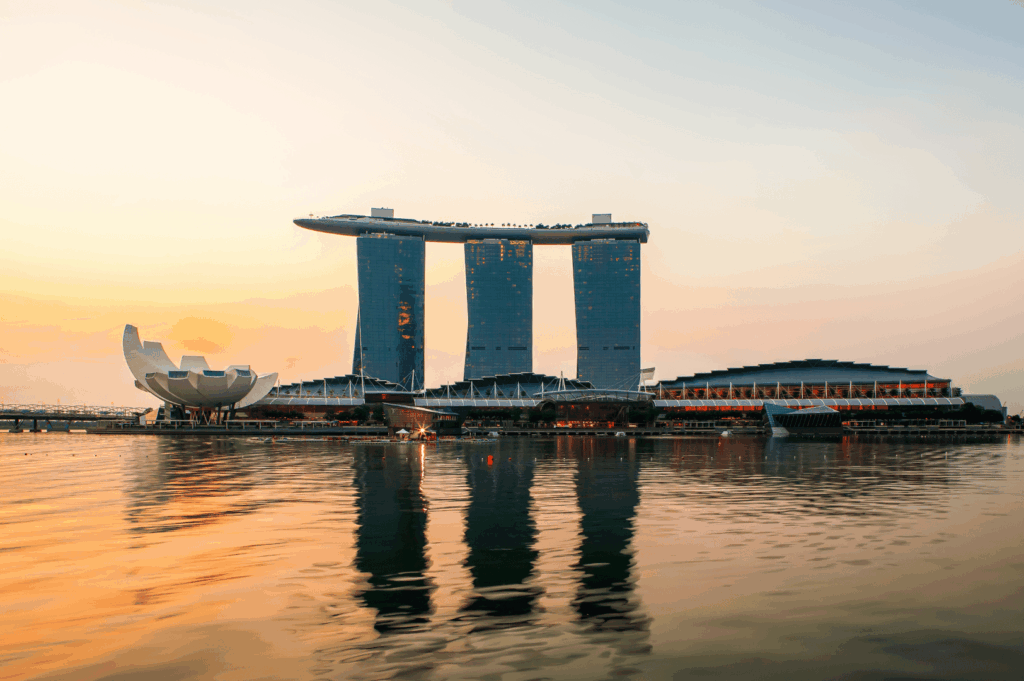 Sunset view of Marina Bay Sands and the ArtScience Museum reflected in tranquil waterfront hues; iconic architecture bathed in warm light captures Singapore’s skyline at its most cinematic—an unforgettable setting for scenic dining.