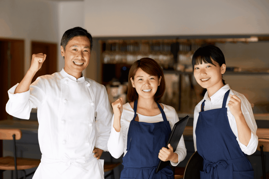 Three smiling restaurant staff members—including a chef in white uniform and two team members in blue aprons—posing together in a fine dining establishment, symbolizing the camaraderie, professionalism, and dedication behind michelin star restaurants. This image reflects the collaborative spirit essential to achieving one michelin star, two michelin stars, or three michelin stars, as evaluated by michelin inspectors using the five criteria outlined in the michelin star restaurant guide. From sous chef to head chef, and young chef to chef owner, teams at fine dining restaurants like Summer Pavilion, Saint Pierre, and those at Marina Bay or Ion Orchard work together to deliver exceptional cuisine, innovative dishes, and memorable dining experiences. World renowned chefs such as chef louis han, chef yew eng tong, head chef takuya yamashita, chef owner emmanuel stroobant, chef denis lucchi, and chef christophe lerouy lead culinary journeys that blend global influences, japanese cuisine, and seasonal ingredients. Michelin introduced the michelin green star and bib gourmand to honor sustainability and good restaurant practices in the hospitality industry, while all the restaurants featured in the michelin guide strive for gastronomic excellence and the first michelin star.