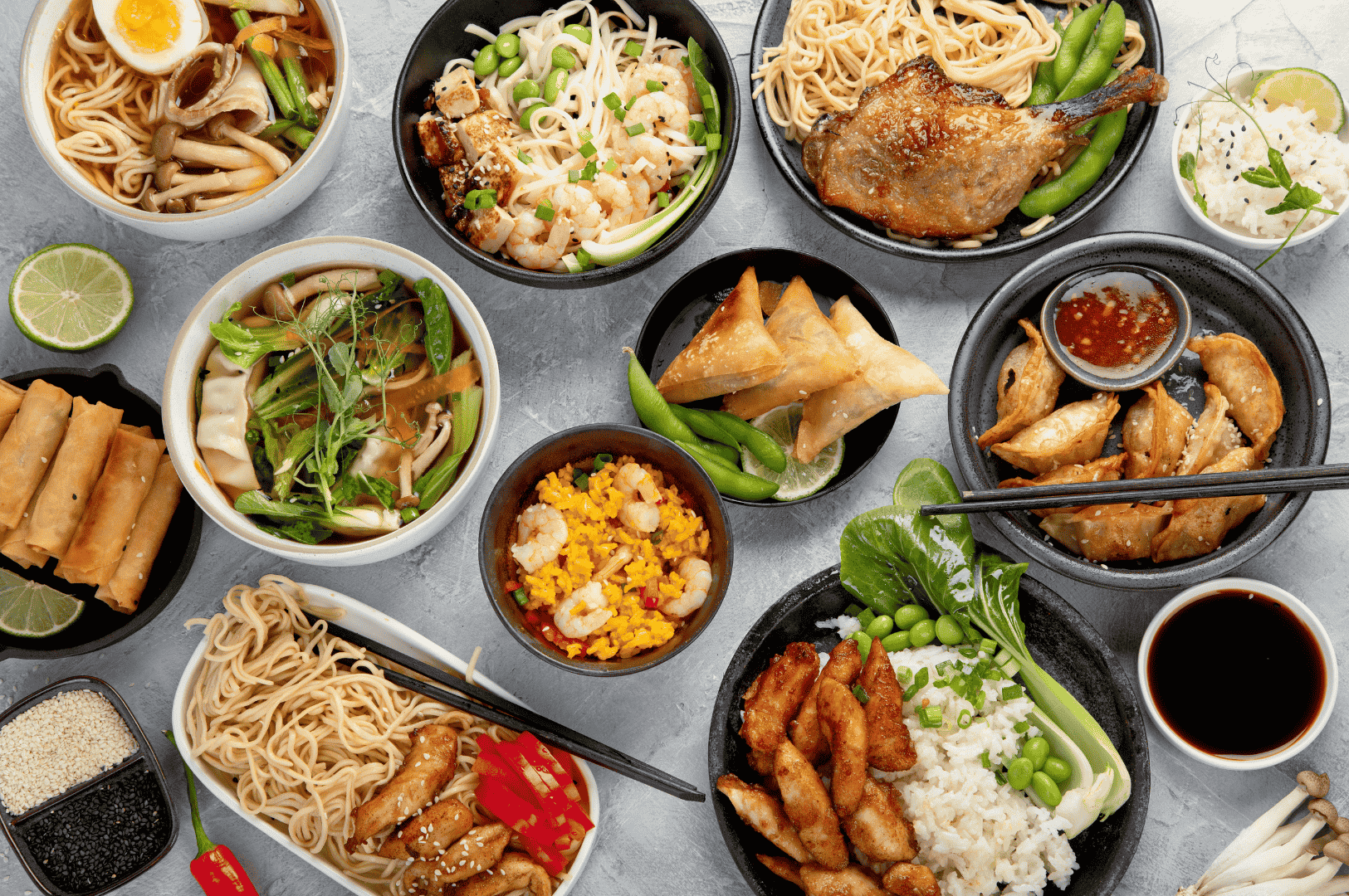 A vibrant array of Asian-inspired dishes arranged on a communal table, featuring noodle bowls with grilled duck and boiled eggs, spring rolls with lime, dumplings, fried rice, and grilled chicken with bok choy and edamame. The composition celebrates the diversity of textures and flavors—crispy, savory, umami-rich—reflecting Singapore’s fusion philosophy where regional traditions converge in bold, modern expressions of comfort food.