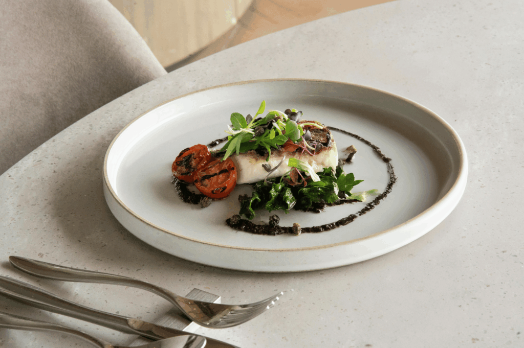 Overhead shot of a refined plant-based dish plated with precision on a white plate atop a wooden table, evoking fine-dining elegance in a Singapore context
