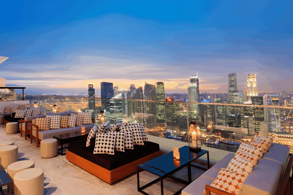 Luxurious rooftop lounge in Singapore at dusk with patterned cushions, candlelit tables, and sweeping skyline views—capturing the city’s transformation into a global destination for elevated dining.