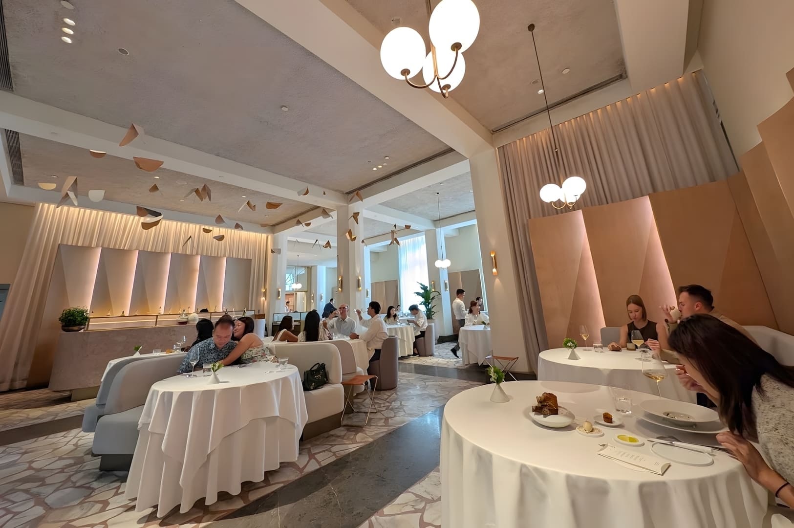 Inside Odette, patrons are seated at tables, engaged in conversation while enjoying their meals in a vibrant setting.