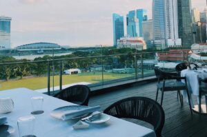 A restaurant in Singapore featuring a stunning view of the city skyline, showcasing modern architecture and vibrant lights.