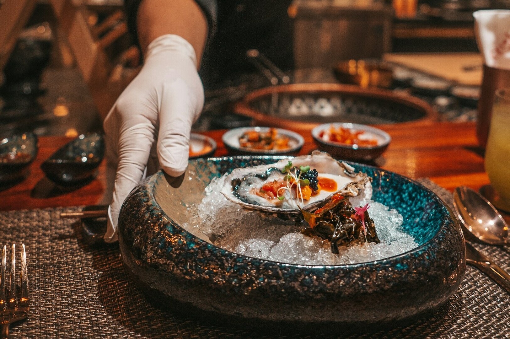 A hand presenting a bowl of oysters on ice, highlighting a gourmet offering from a Michelin Omakase in Singapore.