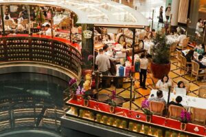 A bustling food court at the Bayfront Avenue featuring various dining options, including Michelin-rated restaurants from Singapore.