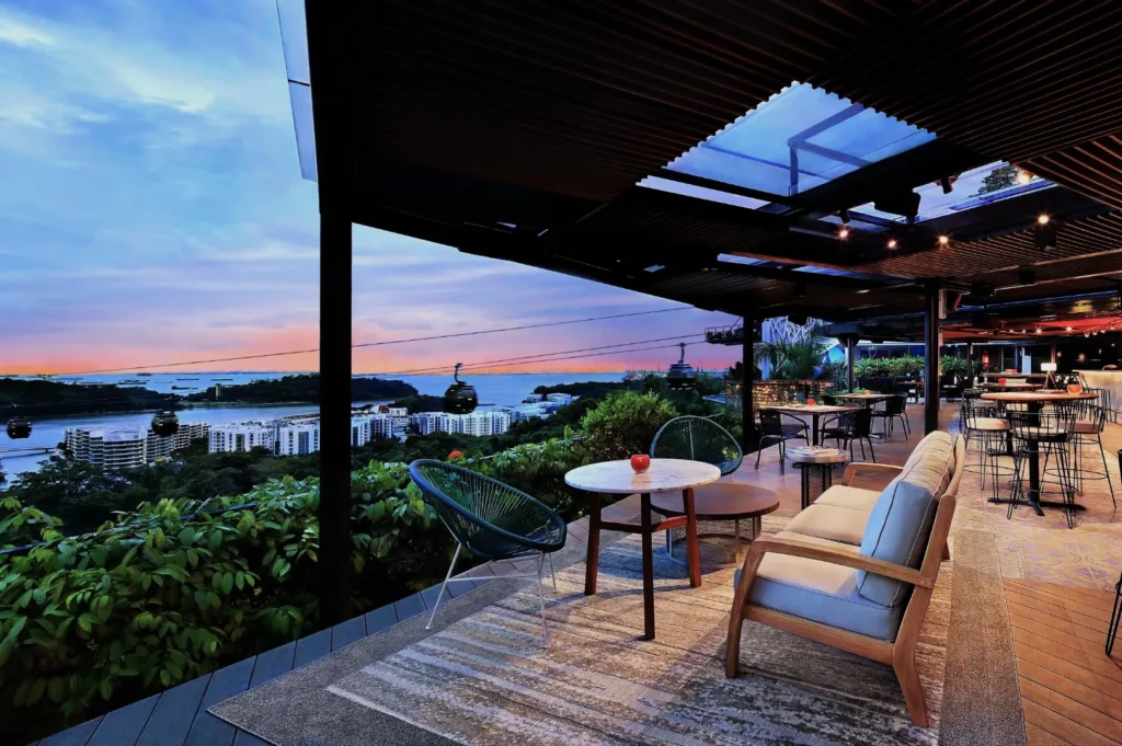 Rooftop terrace with modern seating overlooks a sunset view of the ocean and cable cars, creating a serene and luxurious ambiance.