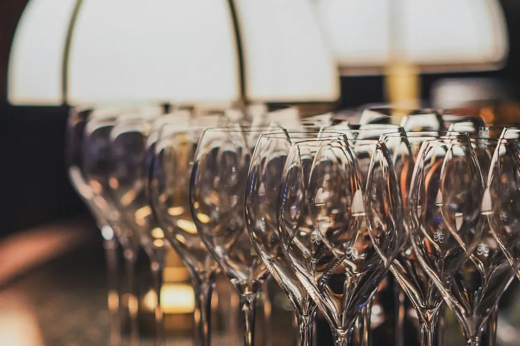 A row of elegant, empty wine glasses with soft lighting and a warm, intimate ambiance, reflecting a fine dining or celebratory setting.