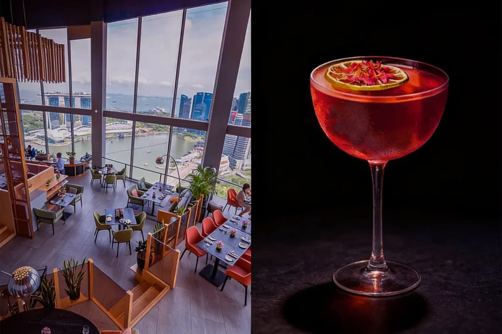 A stylish rooftop restaurant with large windows offers a panoramic city and water view. Adjacent, a vibrant red cocktail garnished with a lime slice exudes elegance.