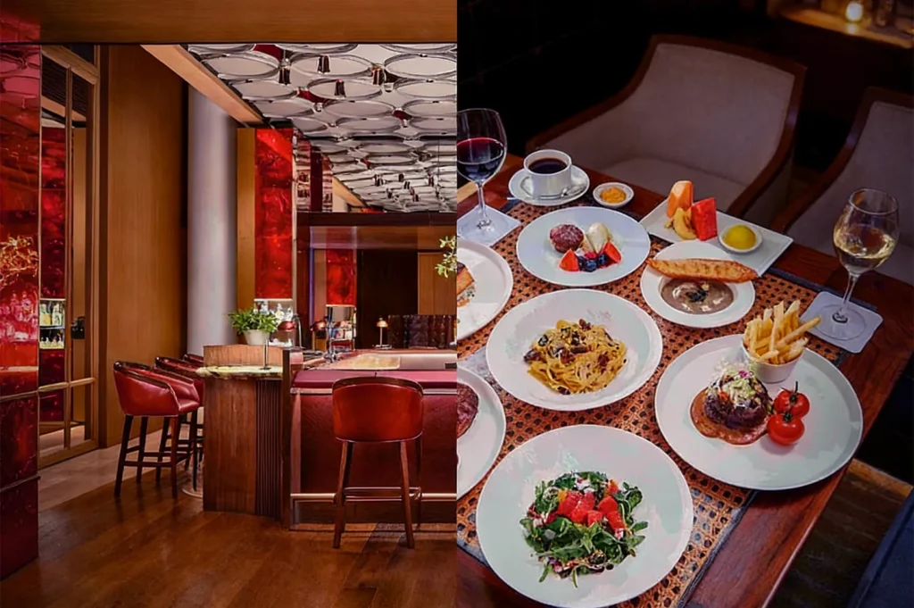 Luxurious restaurant with red decor, cozy wooden interior, and a set table with gourmet dishes. Wine glasses add an elegant, inviting ambiance.