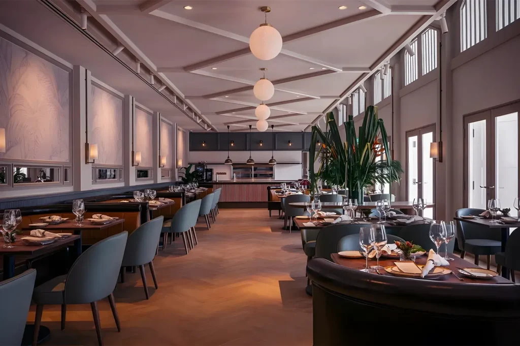 Elegant interior dining room of Bedrock Bar & Grill with mid-century modern furniture, soft globe lighting, and neatly set tables for a fine dining experience.