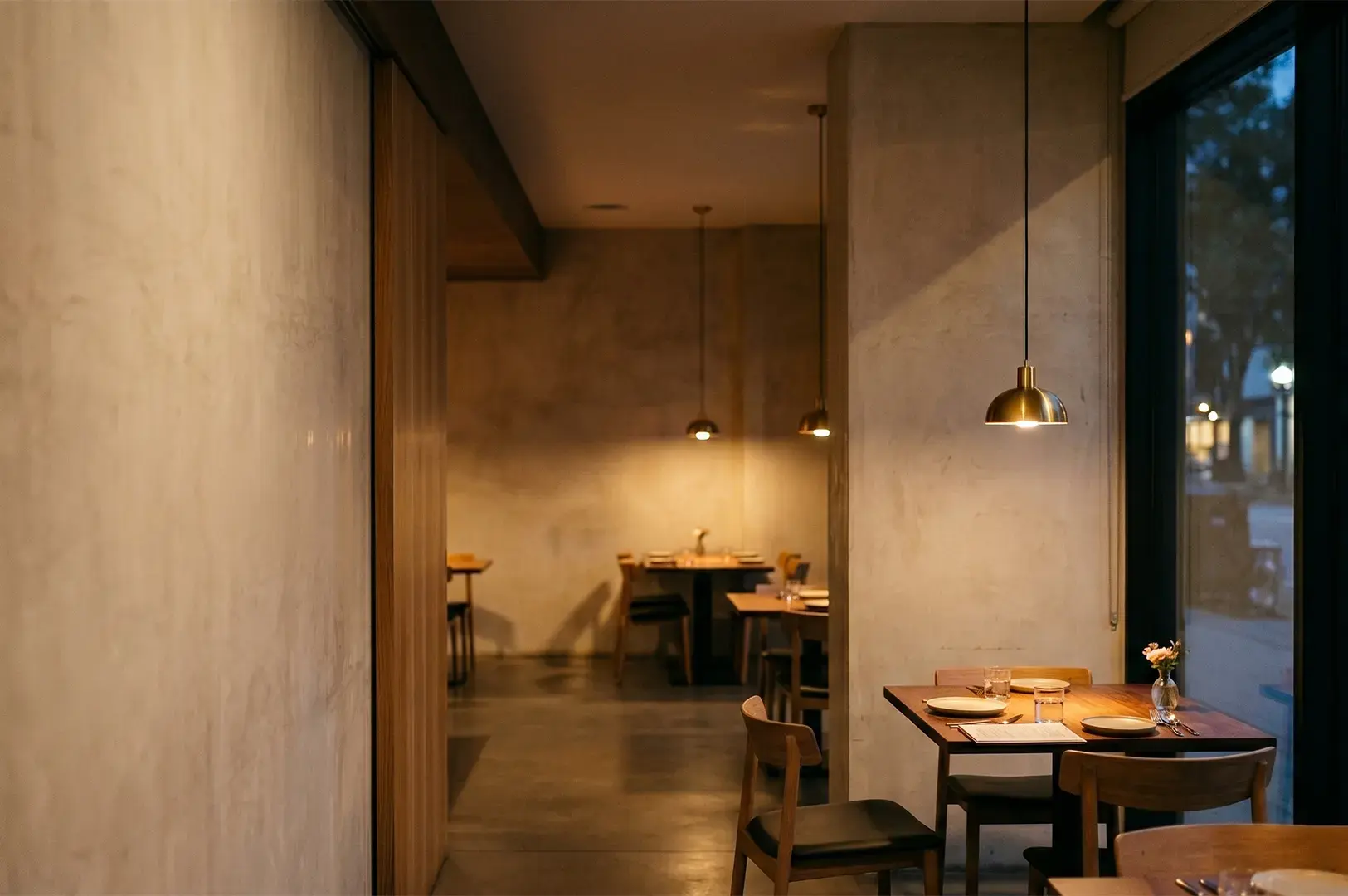 Modern restaurant interior with warm ambient lighting, wooden tables, and minimalist decor.