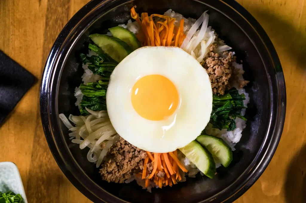 Korean Bibimbap rice bowl with ground beef, vegetables, and a fried egg.
