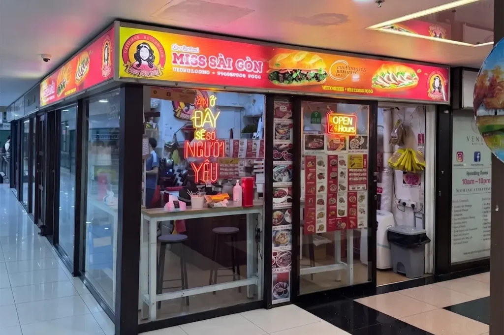 Miss Sài Gòn Vietnamese restaurant storefront at Cuppage Plaza with bright red signboard, menu displays, and 24-hour open sign.